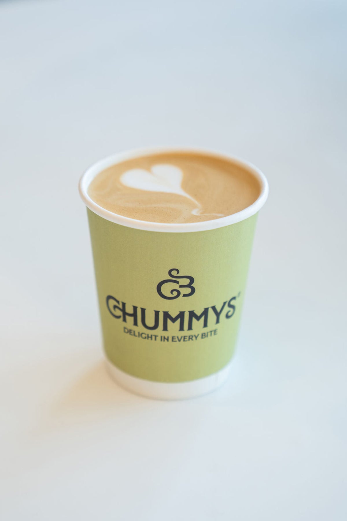 A latte in a green Chummys cup on the counter
